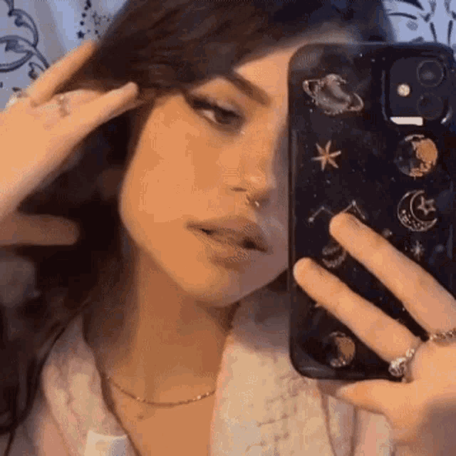 a girl is taking a selfie with her phone in a mirror .