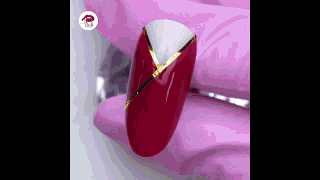a close up of a red nail with a white and gold stripe on it .