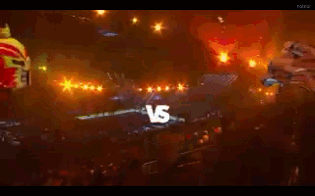 a man in a mask is fighting another man in a mask in front of a crowd in a dark room .