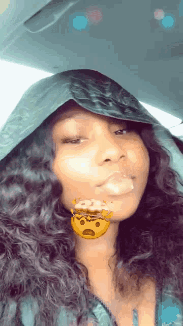 a woman wearing a hooded jacket has a smiley face on her lip
