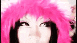 a close up of a woman wearing a pink wig and making a funny face .