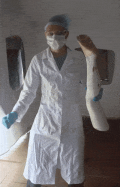 a doctor wearing a white coat and mask holds a leg