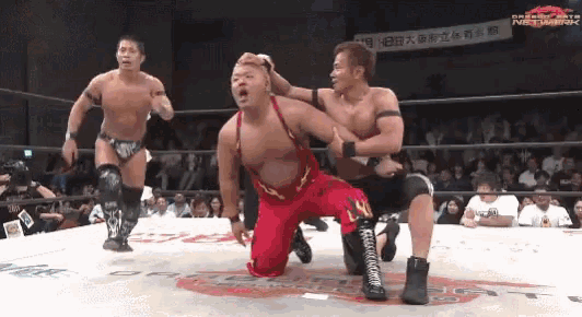 a man in a red outfit is kneeling down in a wrestling ring in front of a banner that says network