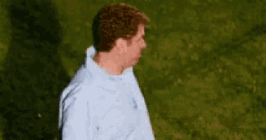 a man in a blue shirt is standing in a field of grass .