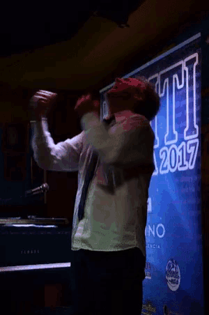 a man singing into a microphone in front of a sign that says mi a 2017