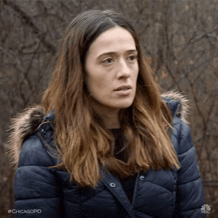 a woman in a blue jacket with a fur hood is standing in the woods .