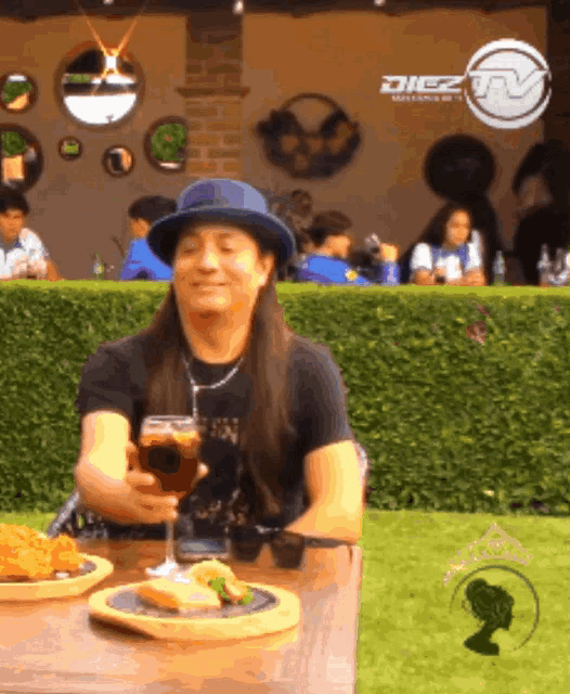 a man is sitting at a table with a glass of wine in front of a sign that says " diez "