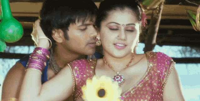 a man kisses a woman on the neck while she holds a flower in her hand