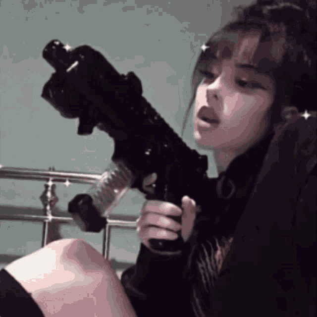 a young girl is sitting on a bed holding a gun .