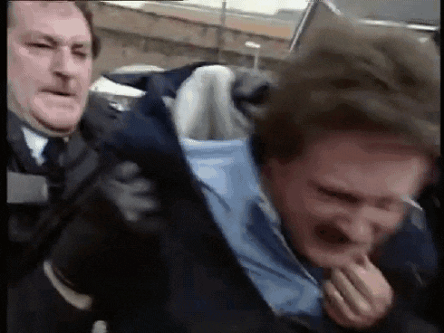 a man in a blue shirt is being held by a man in a suit and tie .