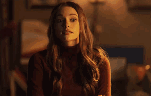a woman in a red sweater is looking at the camera with a surprised look on her face