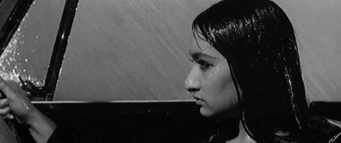 a woman with long hair is sitting in a car in the rain .