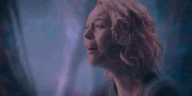 a close up of a woman 's face in a dark room looking out a window .