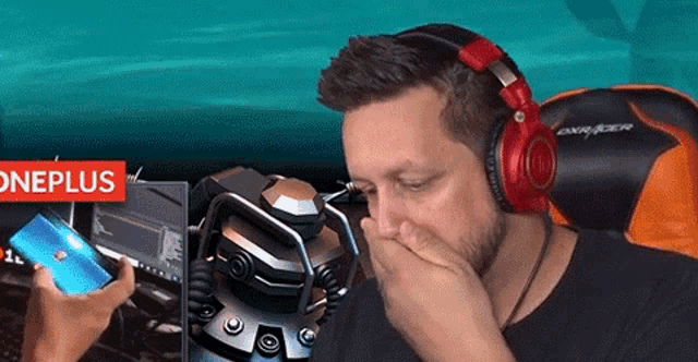 a man wearing headphones is covering his mouth while looking at a phone