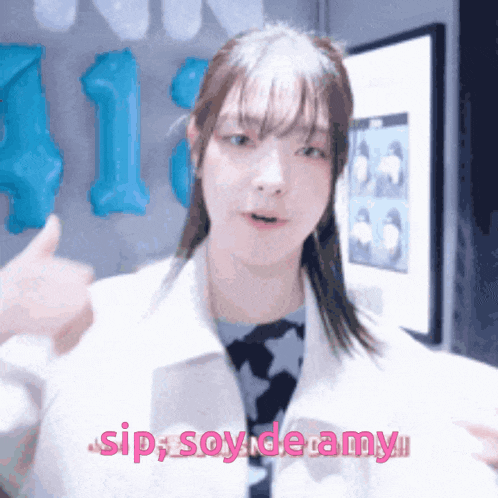 a girl giving a thumbs up with the words " sip soy de amy " behind her
