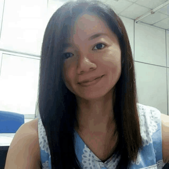 a woman with long dark hair is smiling and wearing a blue shirt .