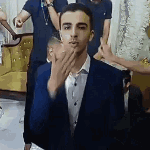 a man in a suit is blowing a kiss in front of a crowd of people .