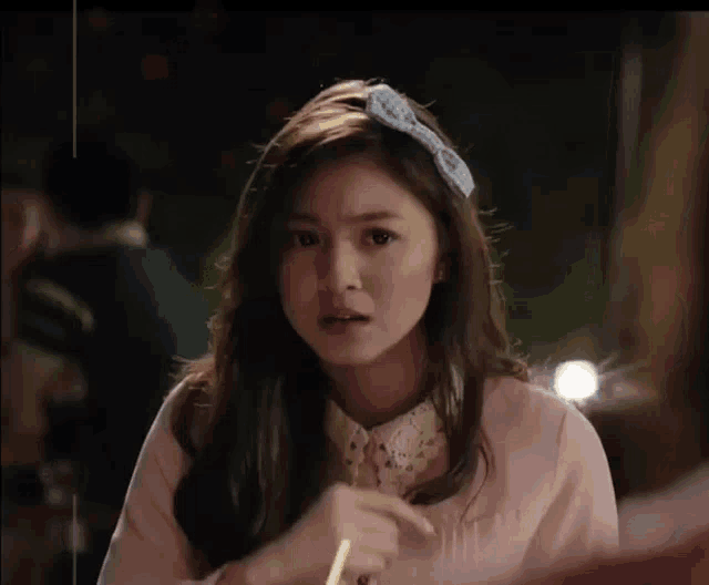 a woman wearing a headband with a bow on it looks surprised