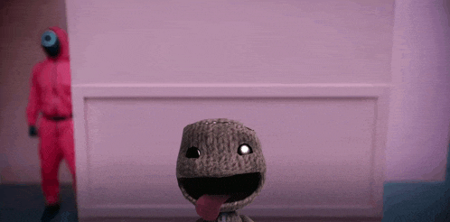 a person in a red suit is standing behind a stuffed animal with a tongue sticking out .