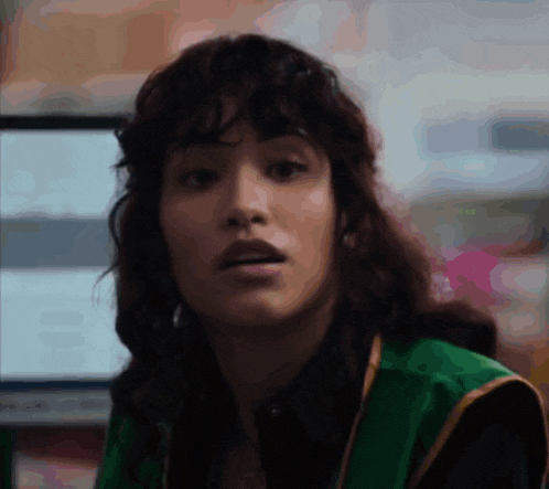a woman with curly hair and a green vest