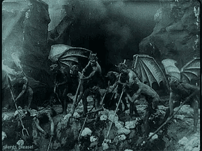 a black and white photo of a group of devils standing in a cave .
