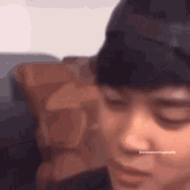 a close up of a person 's face with their eyes closed and a beanie on .