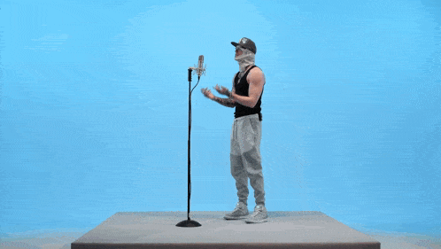 a man with a bandage on his face stands in front of a microphone with his thumbs up