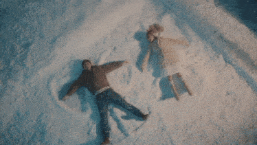 a woman in a white sweater is laying in the snow with her eyes closed .