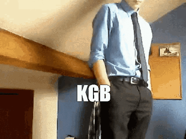 a man in a blue shirt and tie is standing in a room with the word kgb written on the bottom