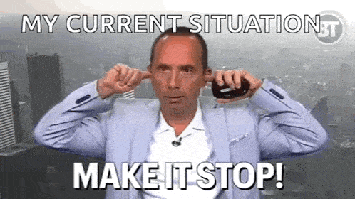 a man in a suit is plugging his ears with his fingers while talking on a cell phone .