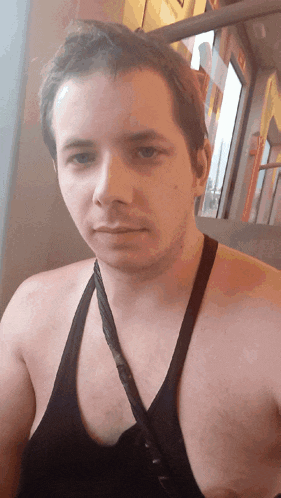 a man wearing a black tank top looks at the camera