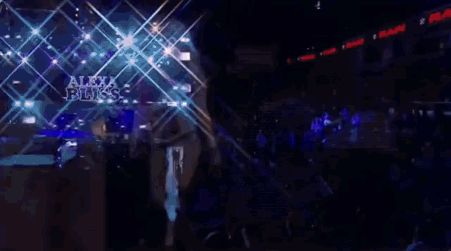 a woman is standing on a stage holding a wrestling belt with the letter w on it .