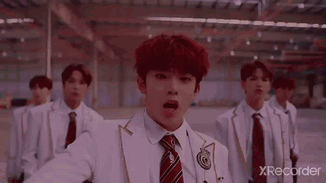 a group of young men wearing suits and ties are standing in a warehouse .