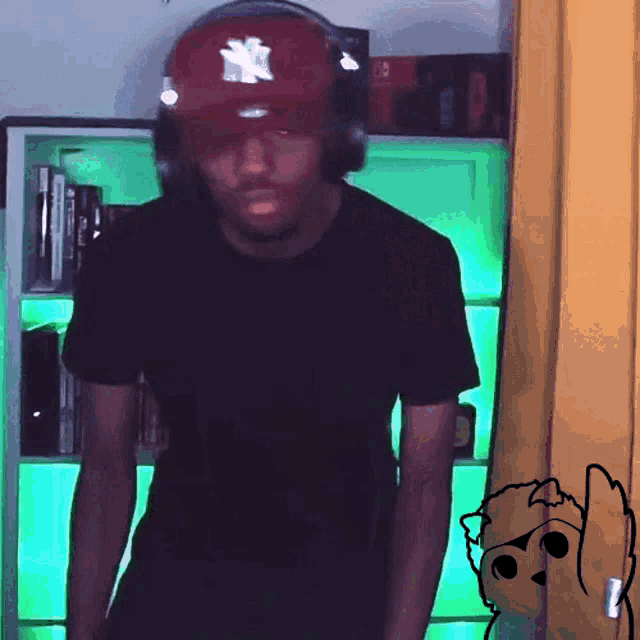 a man wearing a ny hat and headphones stands in front of a green lighted shelf