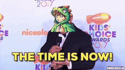 a man in a suit holding a microphone with the words " the time is now " behind him