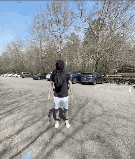 a man standing in a parking lot wearing a black scarf around his head