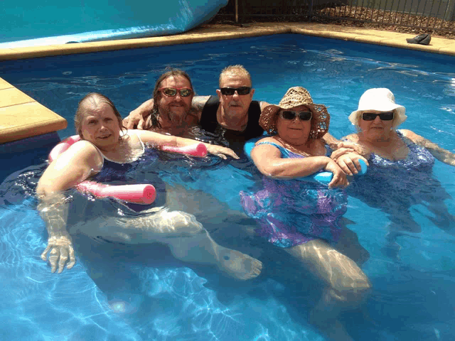 a group of people are sitting in a swimming pool with floats