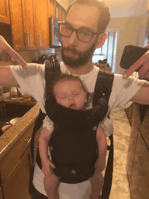 a man is holding a baby in a carrier