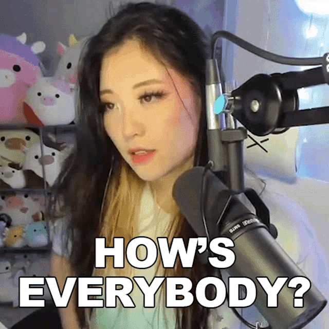 a woman is standing in front of a microphone and says how 's everybody ?