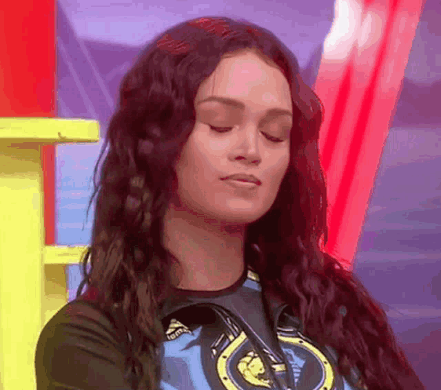 a woman with her eyes closed is wearing a shirt with a horseshoe logo on it