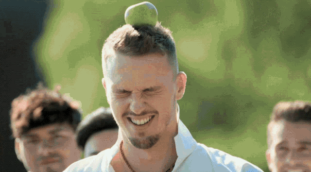 a man with a green apple on his head is smiling
