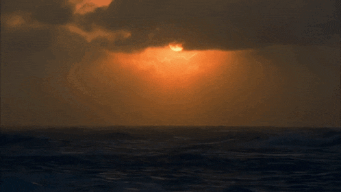 a sunset over the ocean with a few clouds in the sky