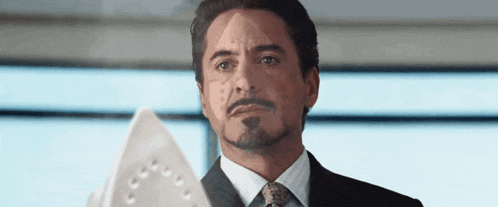 a man in a suit is holding an iron in his hand