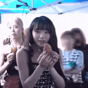 a woman is holding a piece of food in her hands while standing in front of a crowd .