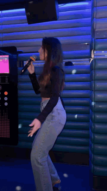 a woman singing into a microphone in a room