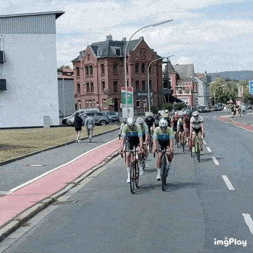 a group of cyclists are riding down a street with a sign that says imgplay on it