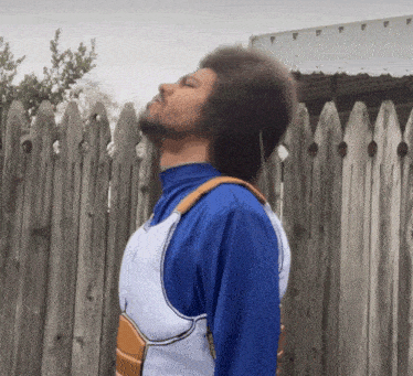 a man in a superhero costume is standing in front of a wooden fence