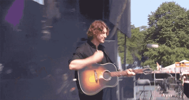 a man in a black shirt is playing an acoustic guitar in front of a crowd