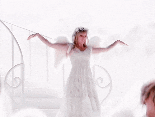 a woman in a white dress with angel wings on her head