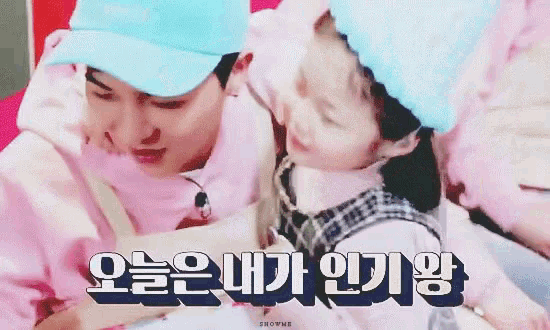 a man in a blue hat is holding a little girl in a pink dress .